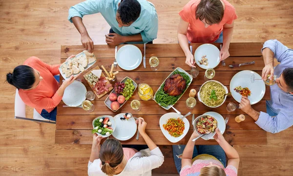 Grupo de pessoas comendo à mesa com alimentos — Fotografia de Stock