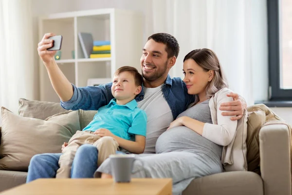Счастливая семья делает селфи со смартфоном дома — стоковое фото
