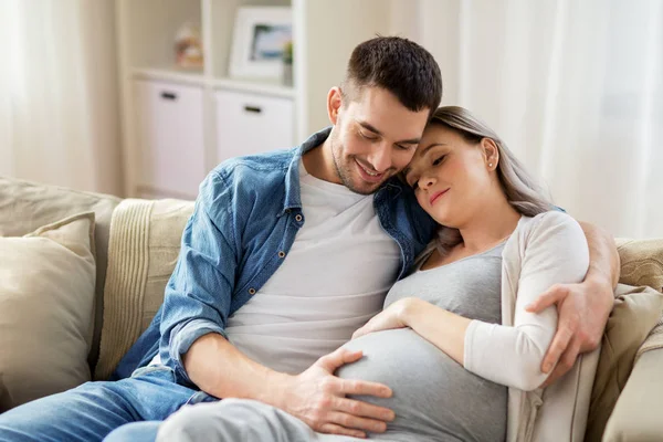 Мужчина обнимает беременную женщину дома — стоковое фото