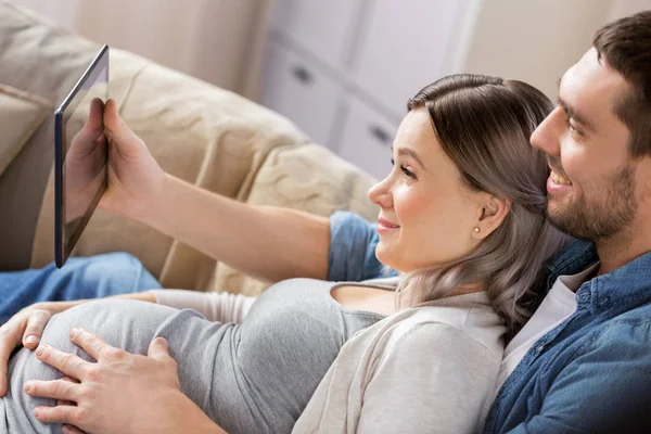 Hombre y mujer embarazada con tableta pc en casa — Foto de Stock