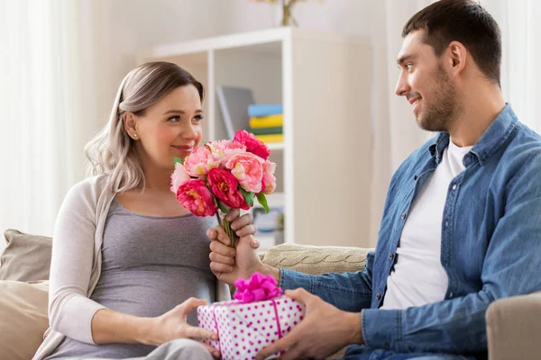 Man ger blommor till gravid kvinna hemma — Stockfoto