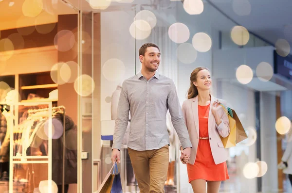 Happy young couple with shopping bags in mall — Stock Photo, Image