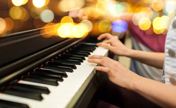 Primer plano de las manos de la mujer tocando el piano sobre luces — Foto de Stock