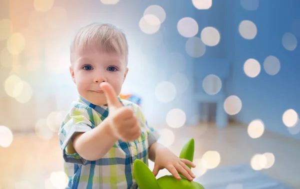 Fröhlicher kleiner Junge spielt mit Spielzeug, das Daumen nach oben zeigt — Stockfoto