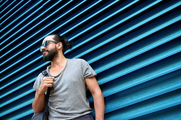 Muž v sluneční brýle s vak stojící na ulici zeď — Stock fotografie
