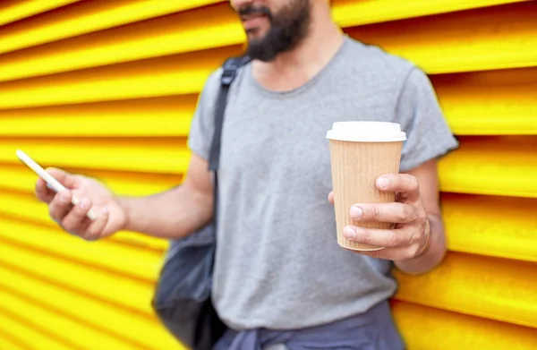 Man with coffee cup and smartphone over wall — Stock Photo, Image