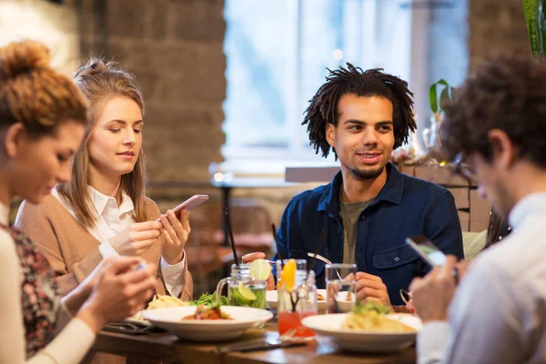 Vrienden met smartphones bij bar of het restaurant — Stockfoto