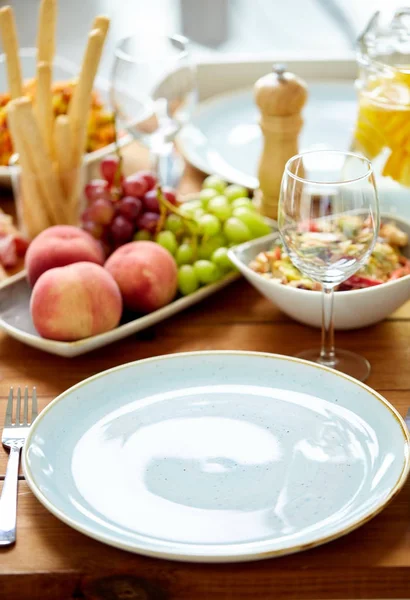 Empty plate and wine glass on table with food — Stock Photo, Image