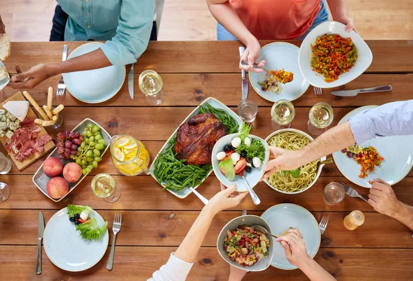 Grupo de pessoas comendo à mesa com alimentos — Fotografia de Stock