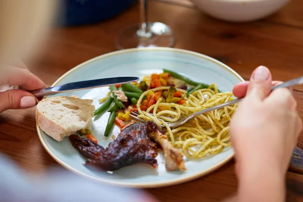 Hands of woman eating pasta and roast chicken — Stock Photo, Image