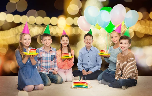 Щасливі діти на вечірніх капелюхах з тортами на день народження — стокове фото