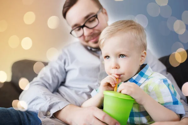 Father and son drinking from cup at home — Stock Photo, Image