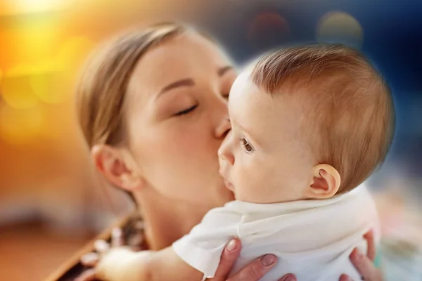 Närbild på glad ung mamma kysser lilla bebis — Stockfoto