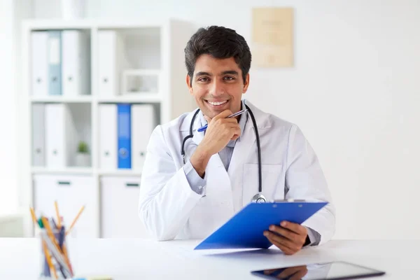 Happy doctor with clipboard at clinic — Stock Photo, Image