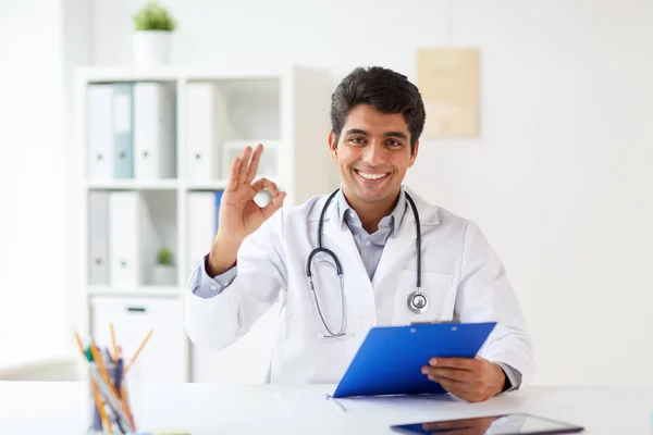 Médico feliz com área de transferência na clínica mostrando ok — Fotografia de Stock