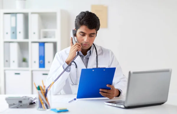 Läkare med Urklipp ringa på telefon på kliniken — Stockfoto
