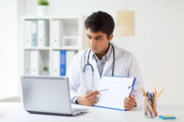 Medico con laptop e cardiogramma in clinica — Foto Stock
