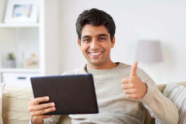 Uomo con tablet pc mostrando pollici a casa — Foto Stock