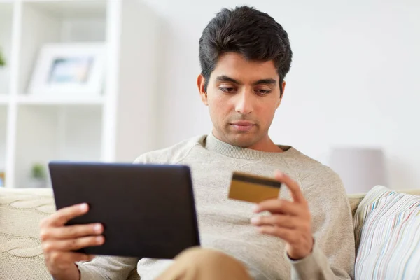 Homem com tablet pc e cartão de crédito em casa — Fotografia de Stock