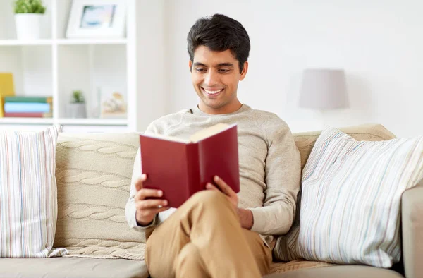 Hombre sentado en el sofá y leyendo libro en casa —  Fotos de Stock