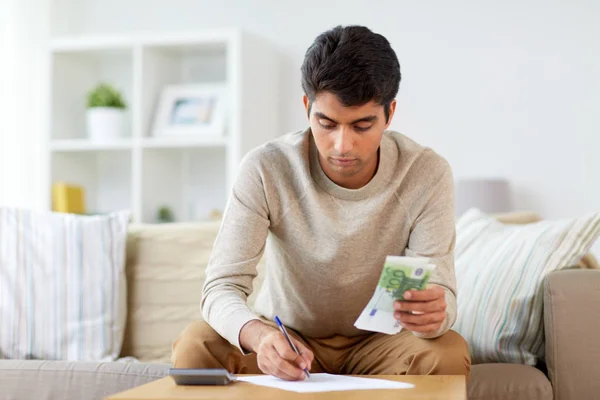 Mann mit Geld und Taschenrechner füllt Papiere aus — Stockfoto