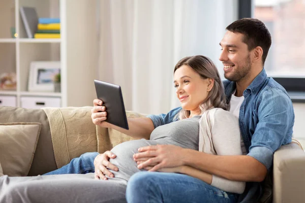 Hombre y mujer embarazada con tableta pc en casa — Foto de Stock