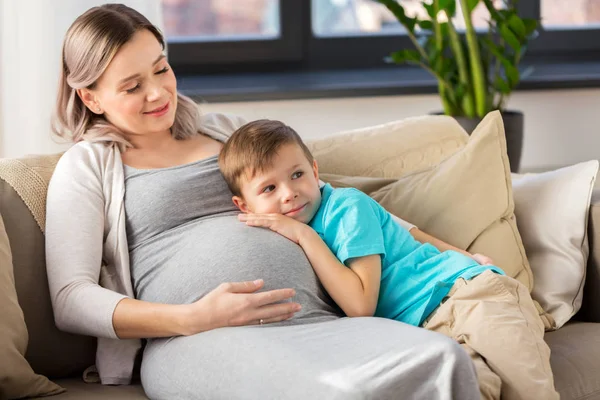 Happy těhotná matka a syn objímání doma — Stock fotografie