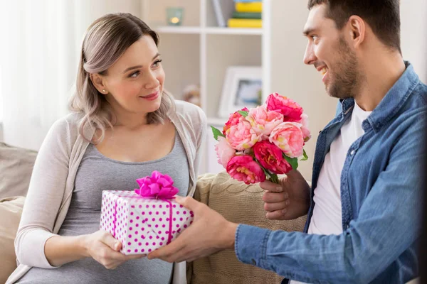 Homme donnant des fleurs à la femme enceinte à la maison — Photo