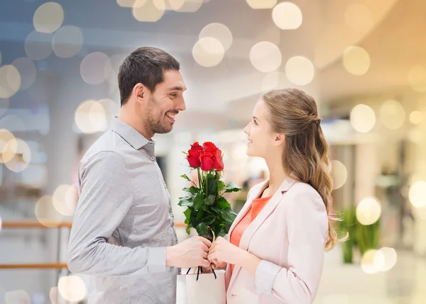 Šťastný mladý pár s květinami v obchoďáku — Stock fotografie