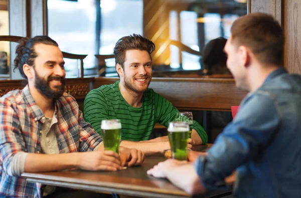 Друзья мужчины пьют зеленое пиво в баре или пабе — стоковое фото