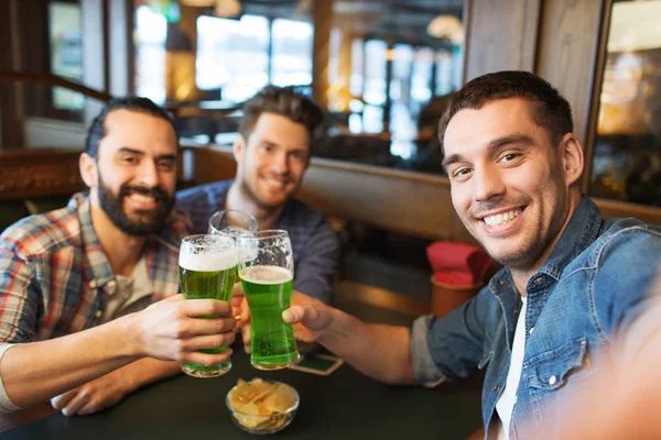 Friends with green beer taking selfie at pub — Stock Photo, Image