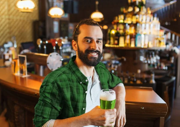 Счастливый человек, пьющий зеленое пиво в баре или пабе — стоковое фото