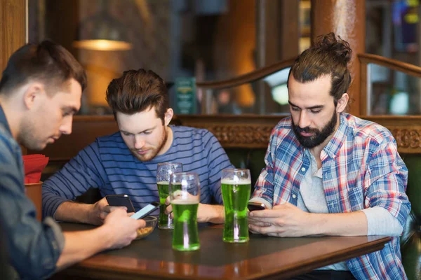 Friends with smartphones and green beer at pub — Stock Photo, Image