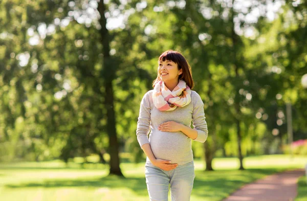 Gelukkig zwangere Aziatische vrouw wandelen in het park — Stockfoto