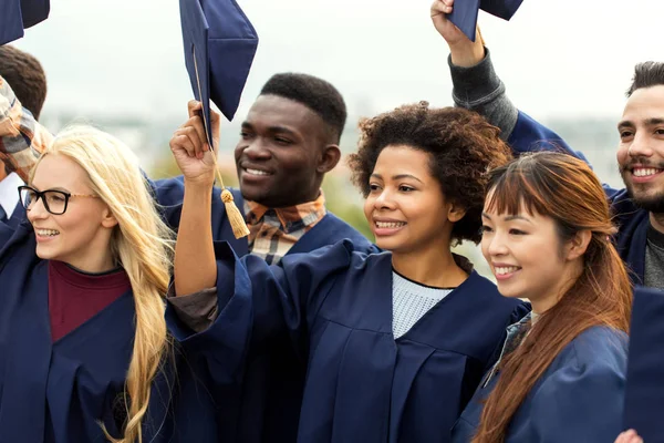 Graduados felizes ou estudantes acenando placas de argamassa — Fotografia de Stock