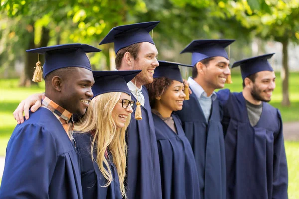 Happy students or bachelors in mortar boards — Stock Photo, Image