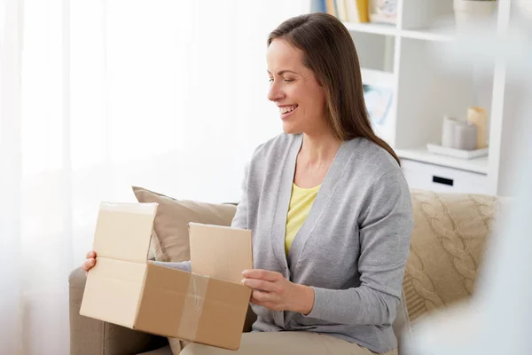 Mujer sonriente abriendo la caja de paquetes en casa —  Fotos de Stock