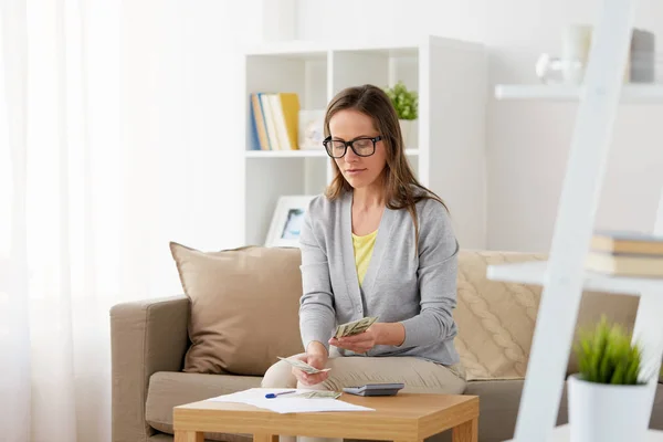 Donna con calcolatrice contare i soldi a casa — Foto Stock