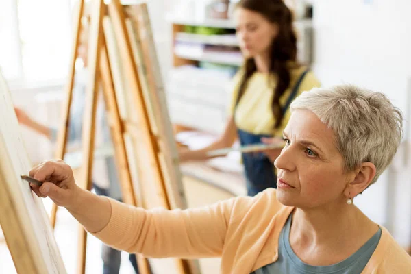 Старша жінка малює на мольберті в студії мистецтв — стокове фото