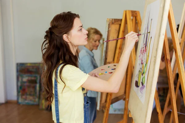 Woman with easel painting at art school studio — Stock Photo, Image