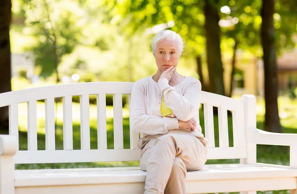 Triste femme âgée assise sur le banc au parc d'été — Photo