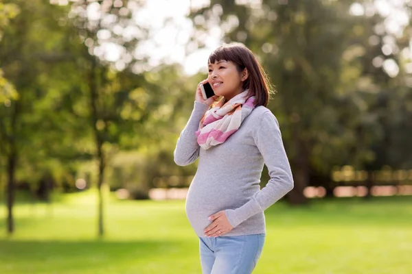 Schwangere Asiatin ruft im Park mit Smartphone an — Stockfoto