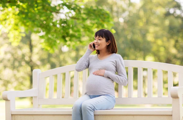 Grávida asiático mulher chamando no smartphone no parque — Fotografia de Stock