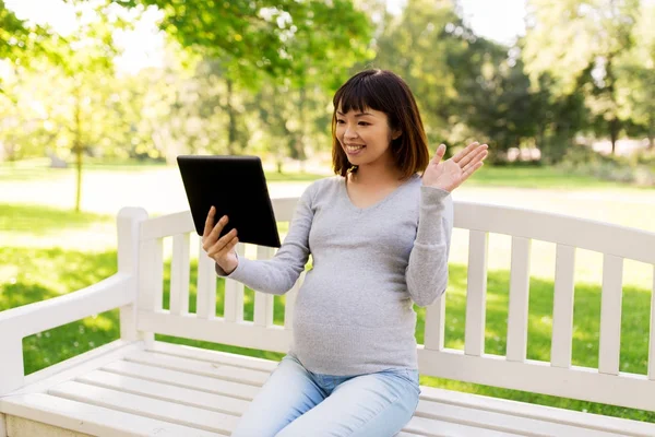 Mujer asiática embarazada feliz con la tableta PC en el parque — Foto de Stock