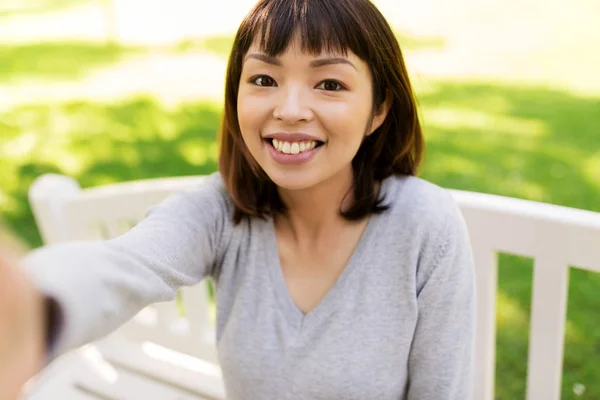 Lyckligt leende asiatisk kvinna tar selfie på park — Stockfoto