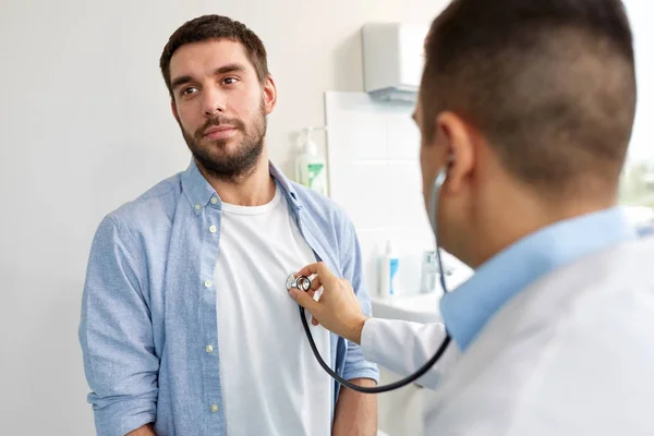 Doctor with stethoscope and patient at hospital — Stock Photo, Image