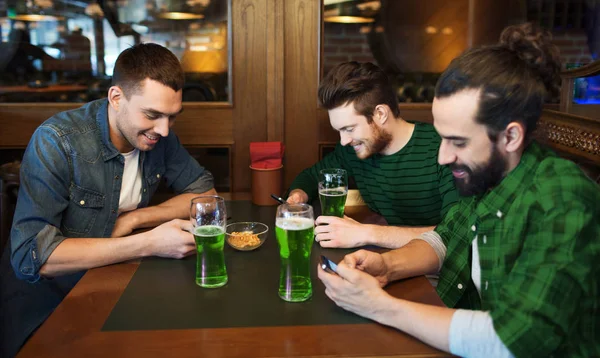 Przyjaciele z smarphones i zielone piwo w pubie — Zdjęcie stockowe