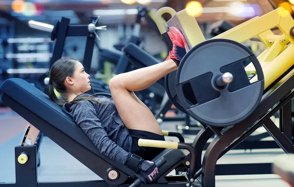 Donna che flette i muscoli sulla pressa per le gambe in palestra — Foto Stock