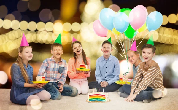 Heureux enfants dans chapeaux de fête avec gâteau d'anniversaire — Photo