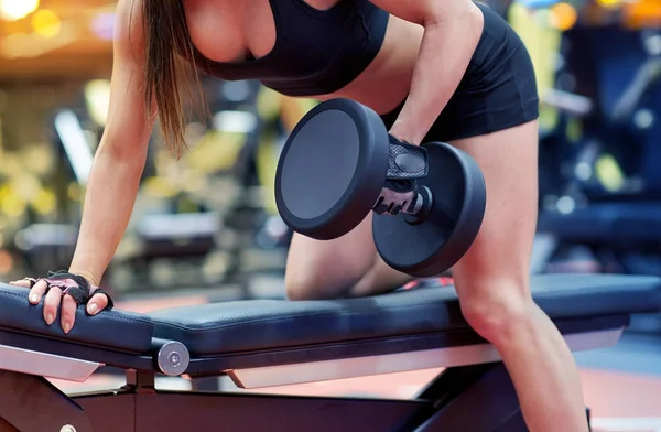 Woman flexing muscles with dumbbell in gym Stock Photo